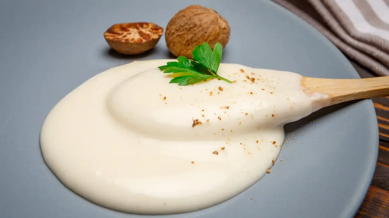 Krämig bechamelsås på en tallrik, med muskotnötter och persilja. Perfekt för ditt bechamelsås recept.
