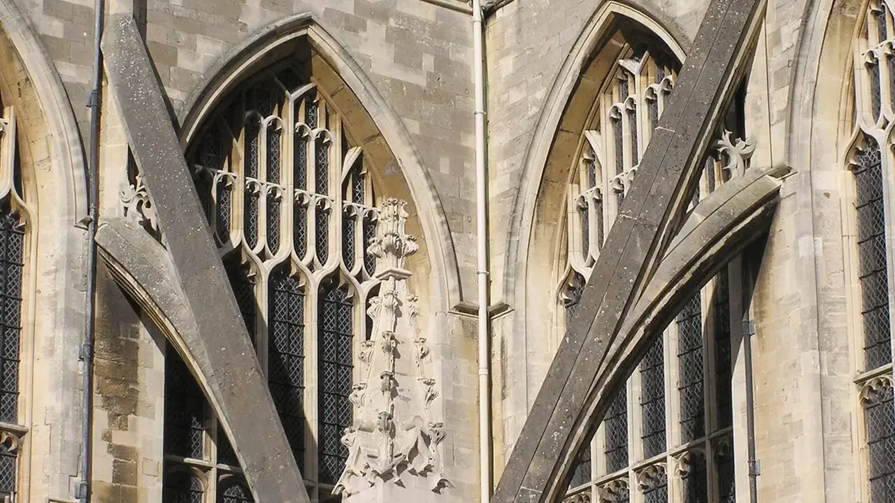 Detalle arquitectónico de una catedral gótica, mostrando la intrincada red de contrafuertes y arbotantes que sostienen sus imponentes muros y ventanas.