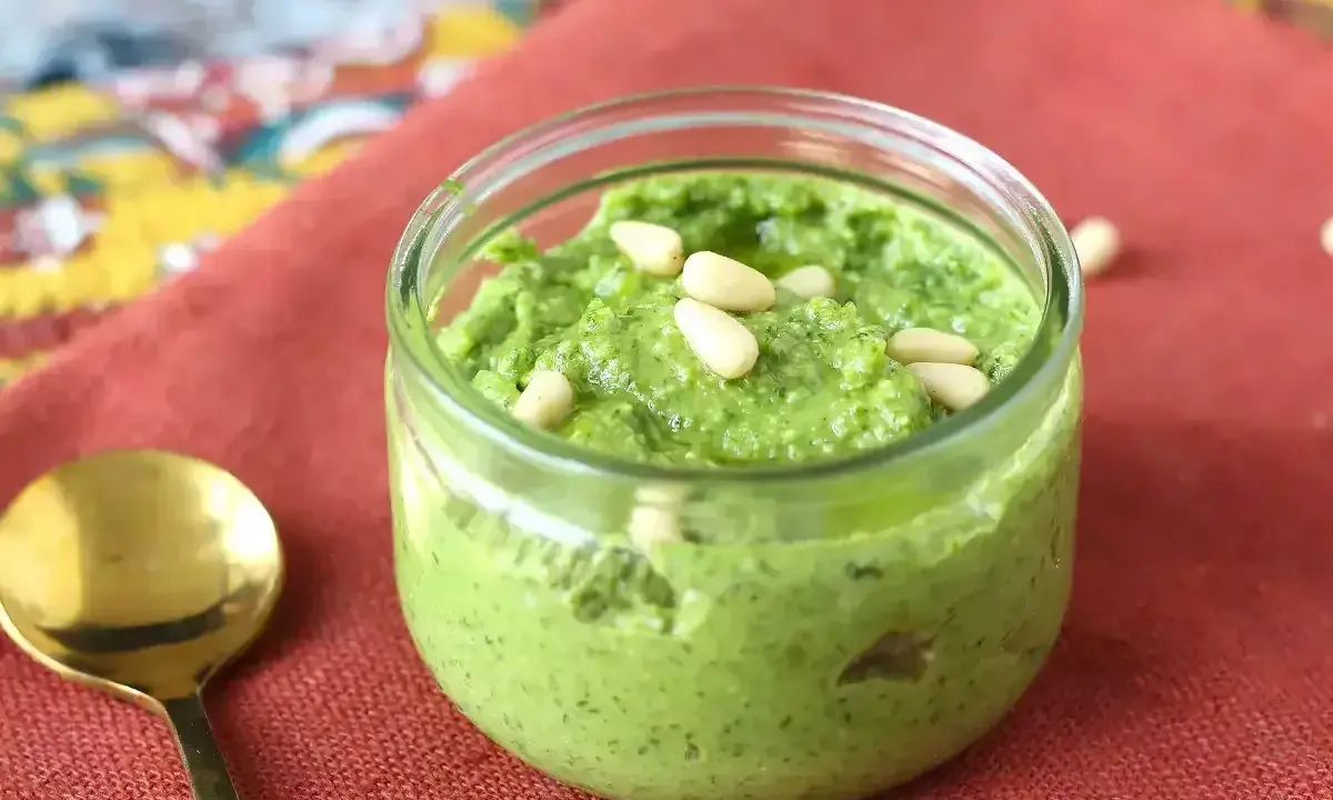 En burk med hemgjord pesto, toppad med pinjenötter. Perfekt för ditt nästa pesto recept!