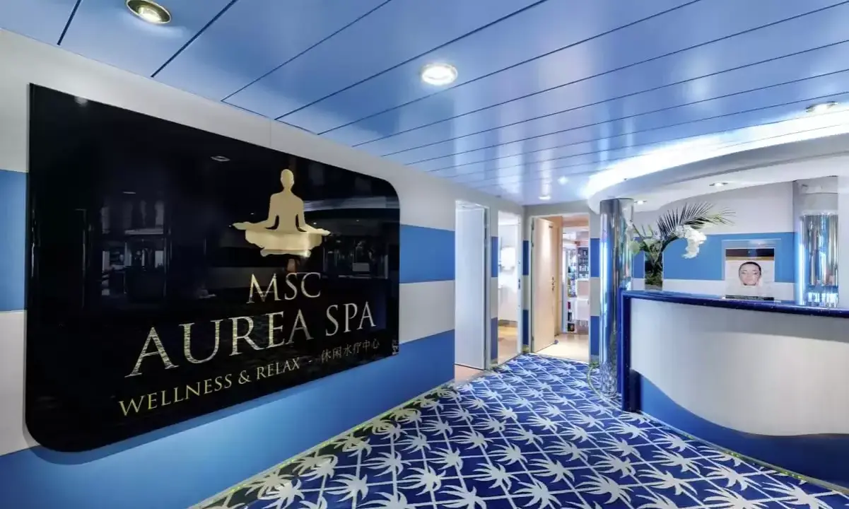 Ingresso della MSC Aurea Spa, con un'insegna dorata su sfondo nero e un tappeto blu con motivi bianchi.