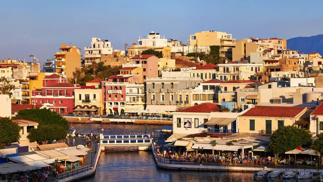 Agios Nikolaos, cosa vedere: un pittoresco porto con case colorate, ristoranti affacciati sull'acqua e un ponte pedonale.