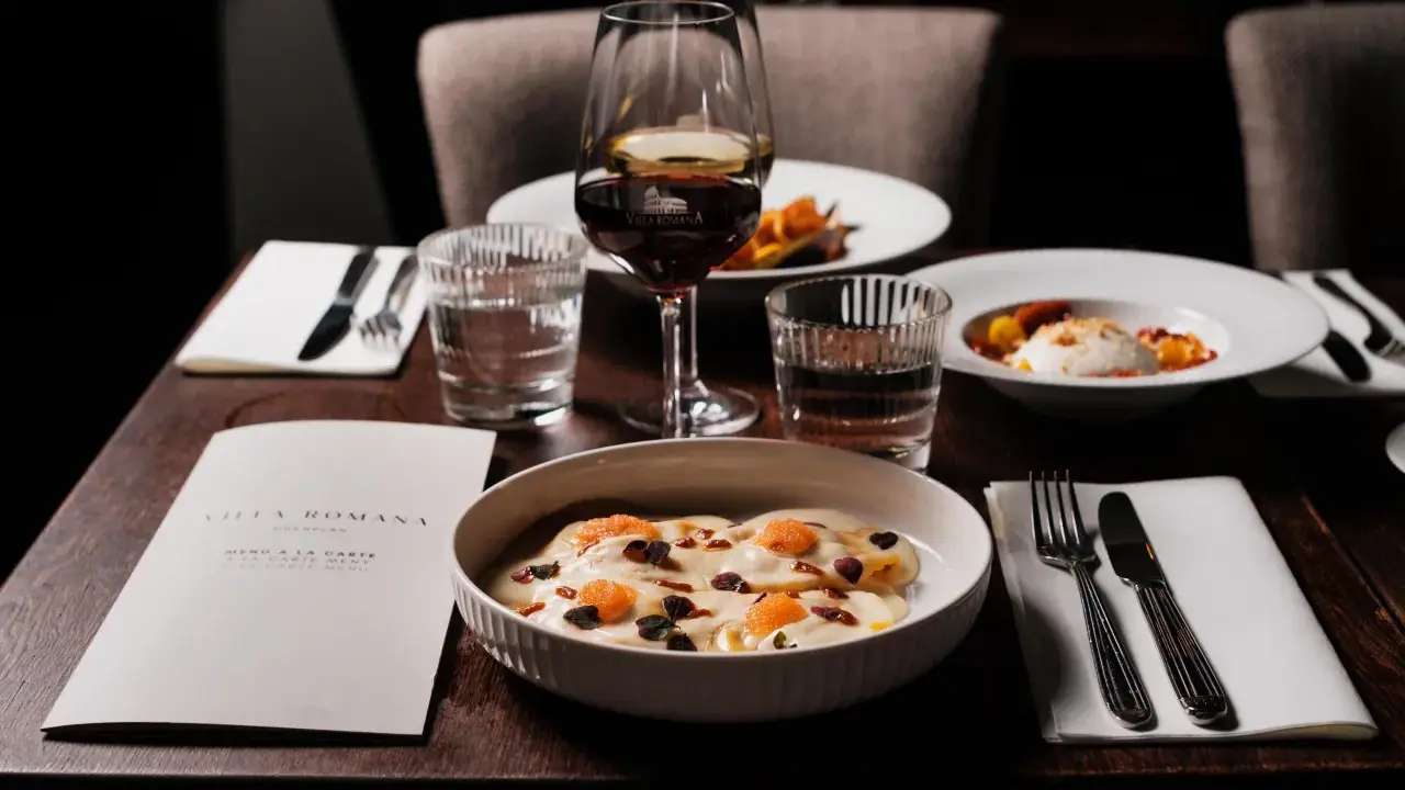 En elegant dukning med italiensk mat, vin och meny från Villa Romana, en av Stockholms bästa italienska restauranger.