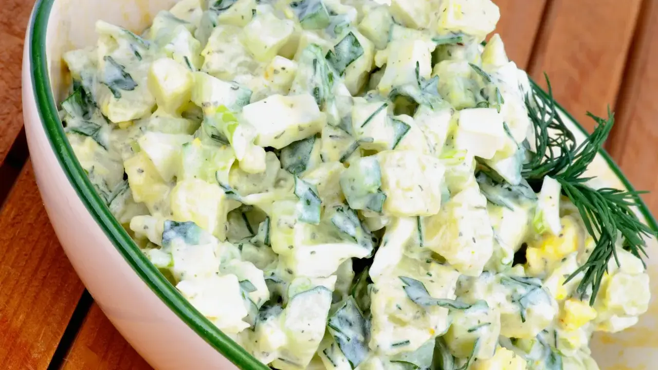 Kartoffelsalat mit Joghurt, Eiern und Gurken, garniert mit Dill. Ein cremiger und erfrischender Salat.