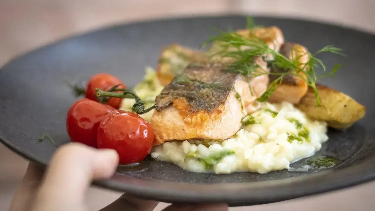 En läcker laxfilé med krämig risotto, körsbärstomater och dill. En perfekt rätt att njuta av, som en del av en **white guide Dalarna**-upplevelse.