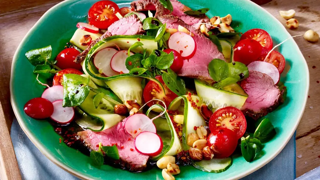 Saftiger Rinderbraten auf einem bunten low carb salat mit Gurke, Radieschen und Kirschtomaten. Nüsse sorgen für Crunch.