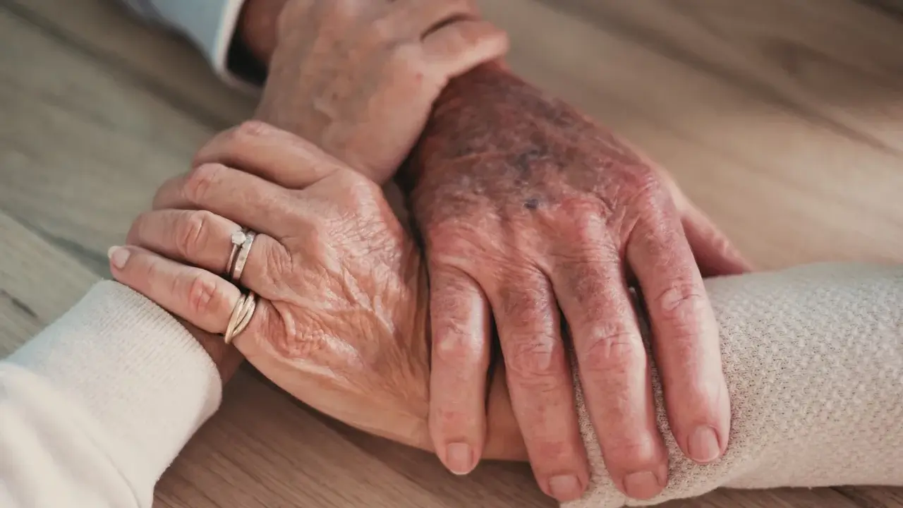 Mains âgées se tenant, symbolisant le soutien et l'amour, même face à un conjoint narcissique.