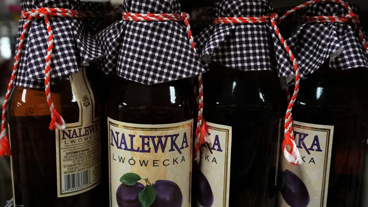 Butelki nalewki lwóweckiej z etykietami i ozdobnymi sznurkami.