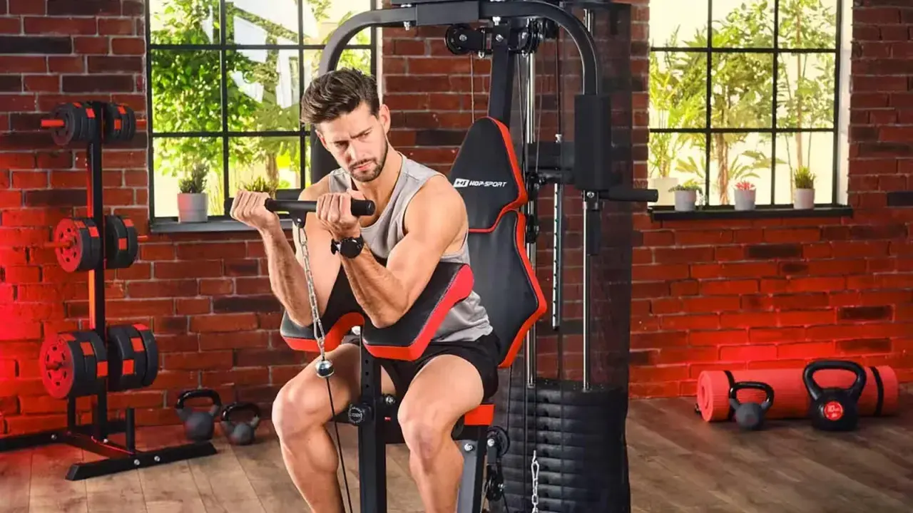 Mężczyzna ćwiczy biceps na domowej siłowni. Sprzęt i akcesoria, jak hantle i kettlebelle, to dowód na to, że polskie marki sportowe oferują wszystko, co potrzebne do treningu.