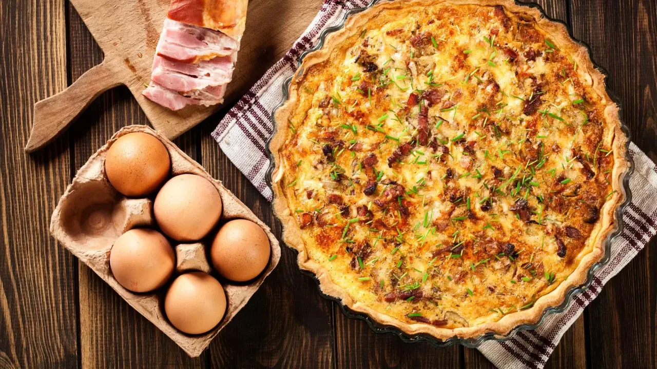 Quiche Lorraine, un classique de la gastronomie lorraine, avec ses ingrédients frais : œufs, lardons et herbes.