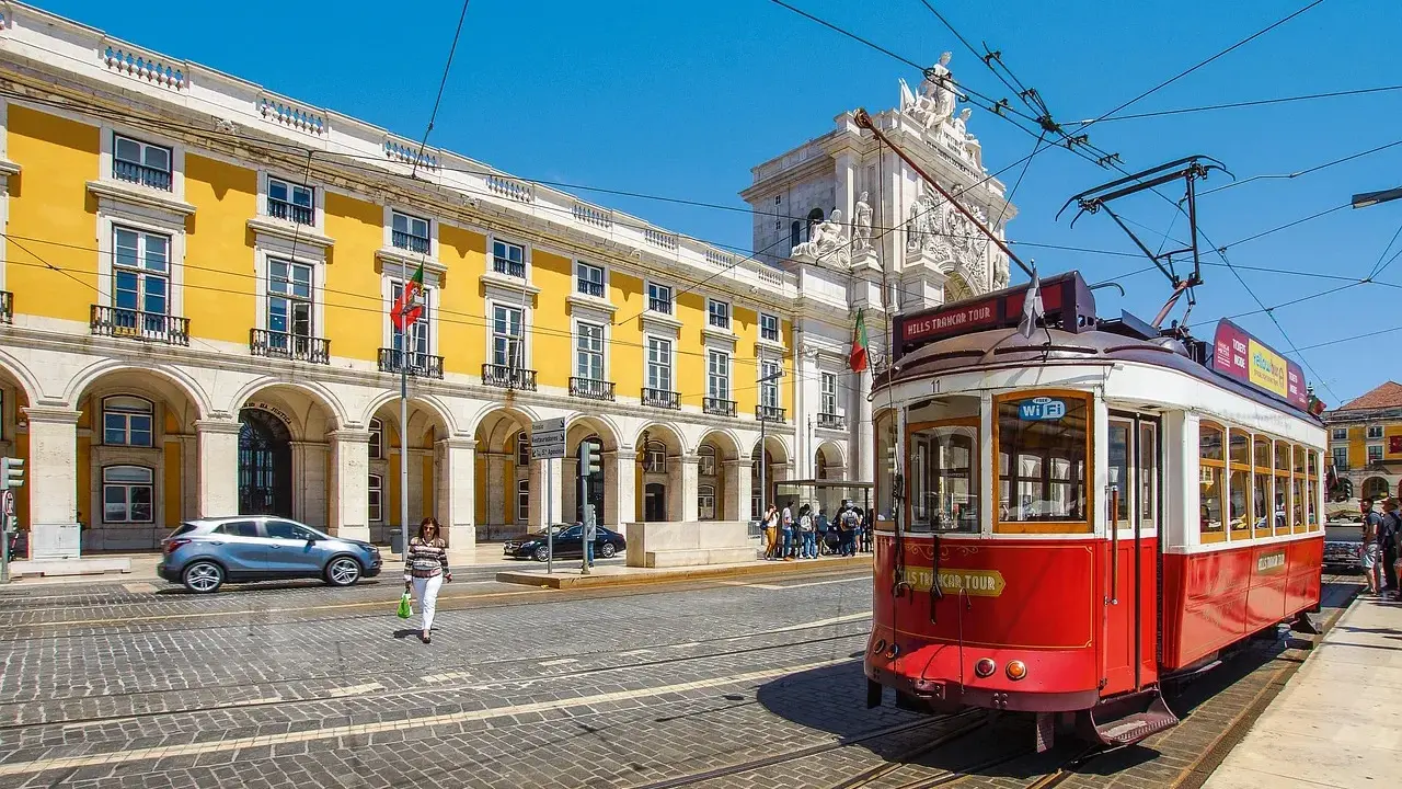 Röd spårvagn i Lissabon, perfekt för en resa med interrail europa. Gula byggnader och en solig dag.