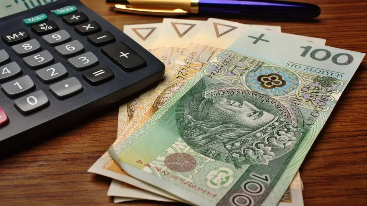 Kalkulator, długopis i polskie banknoty, w tym 100 zł. Przygotowanie do rozliczenia karty podatkowej.