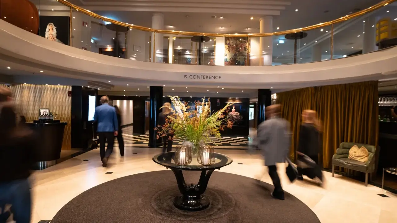 Elegant hotell park lobby med en blomsterdekor i mitten. Människor rör sig förbi i en suddig rörelse.