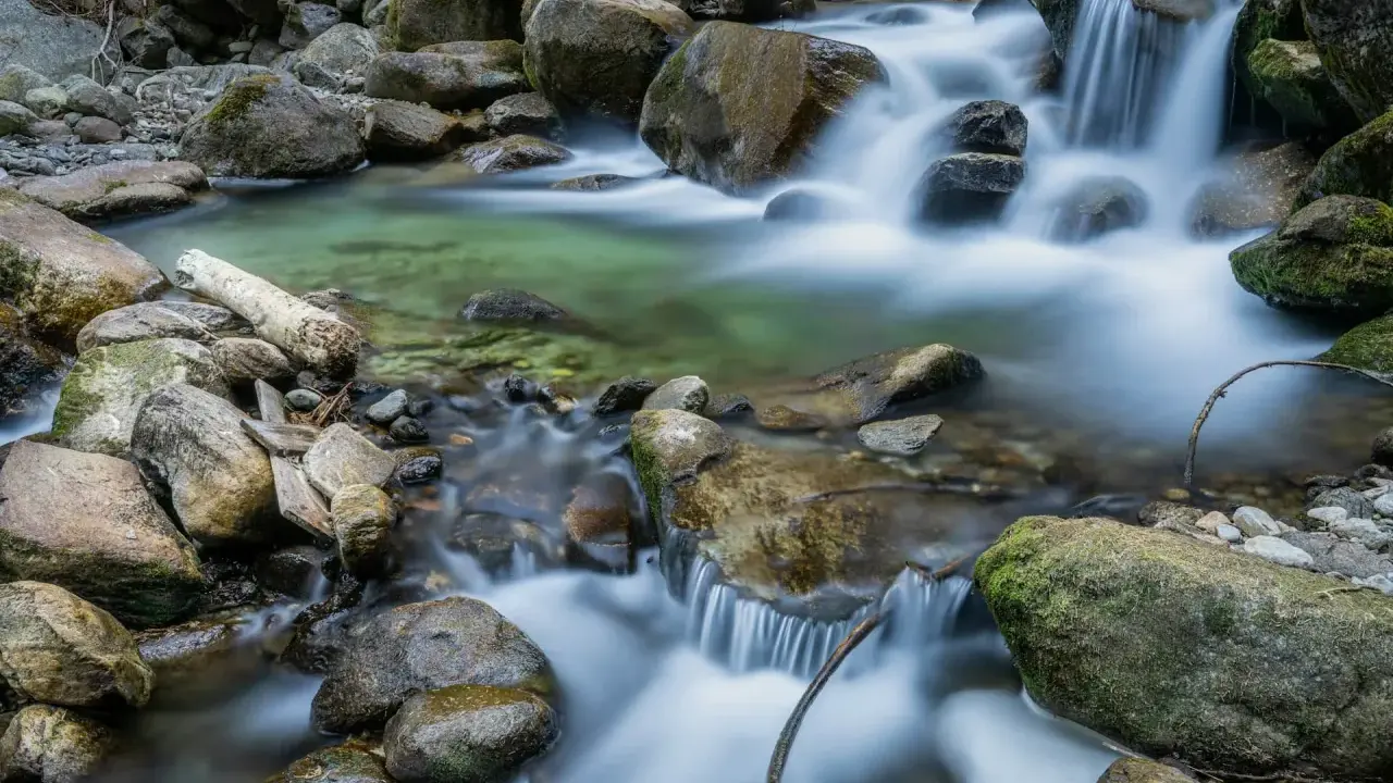 Acqua cristallina scorre tra rocce muschiose, creando un effetto seta su un ruscello di montagna.