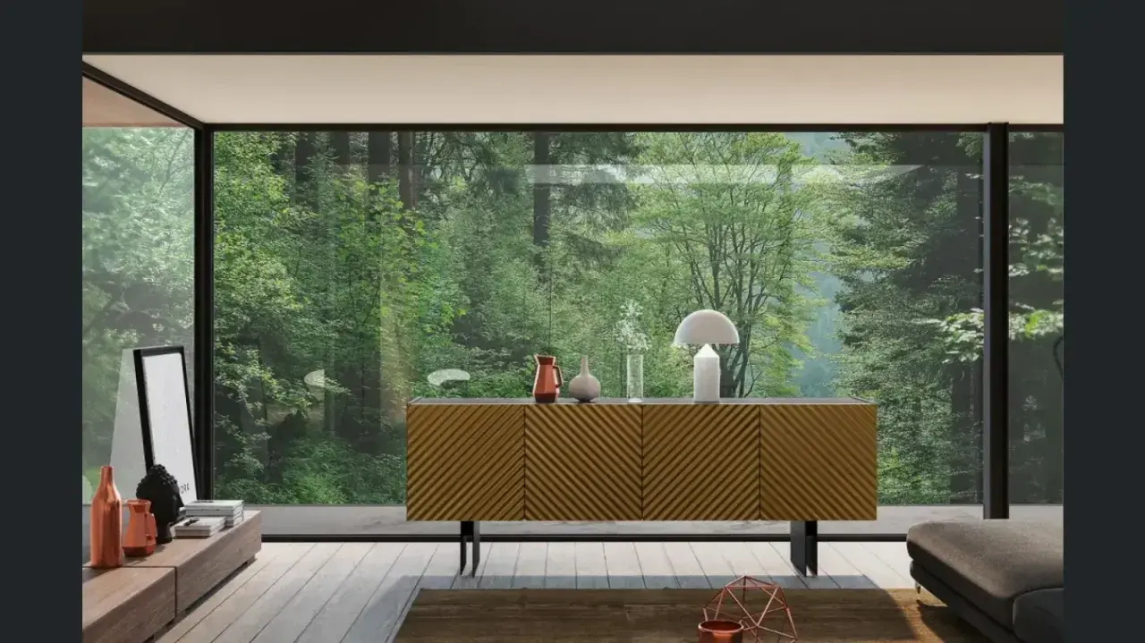 Madia moderna con ante a righe diagonali, un tavolino basso con oggetti decorativi e una grande vetrata su una foresta lussureggiante.