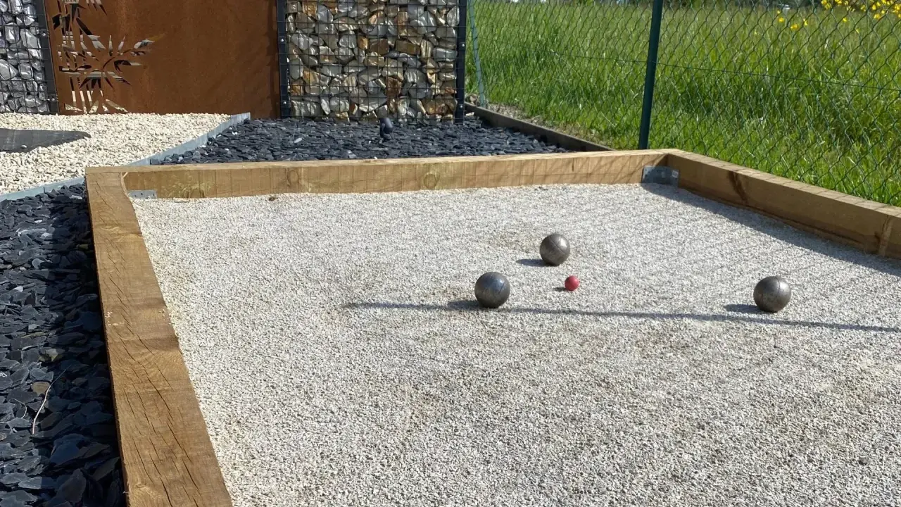 Terrain de pétanque avec boules et cochonnet sur du gravier fin. Le choix du quel sable pour terrain de pétanque est crucial pour un jeu parfait.