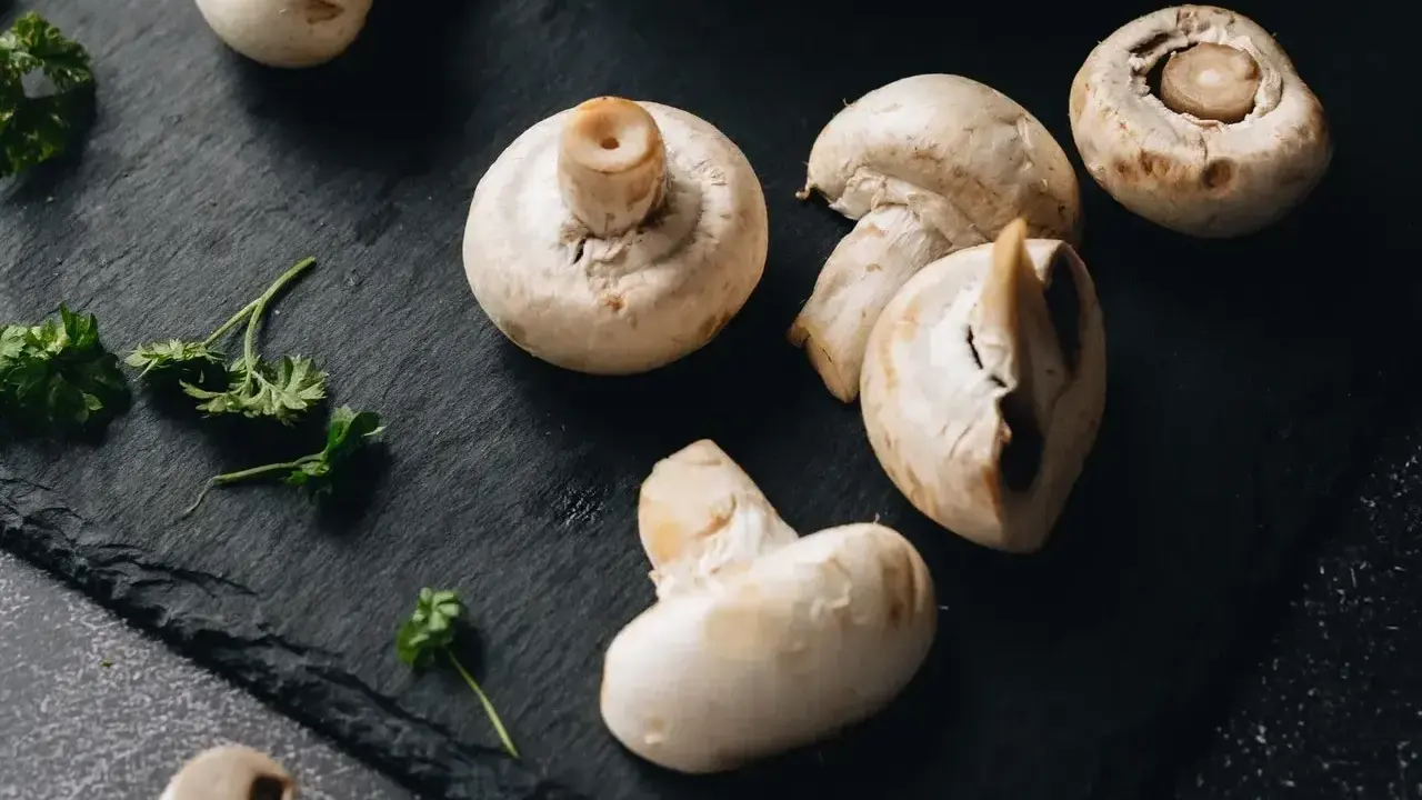 Świeże pieczarki na czarnej desce. Zastanawiasz się, czy pieczarki można mrozić? Tak, można je mrozić, zachowując ich smak i aromat.