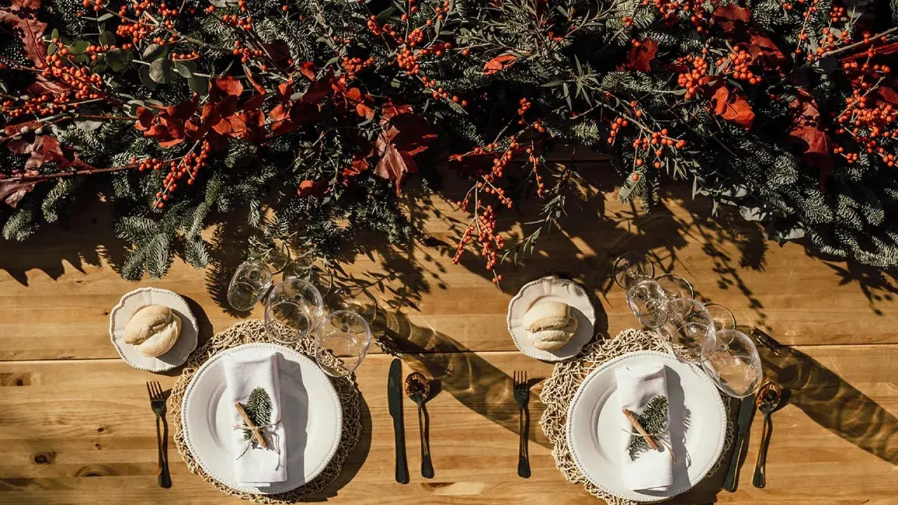 Decoración festiva para una boda en diciembre. Mesa de madera con ramas de pino, bayas rojas y detalles rústicos.