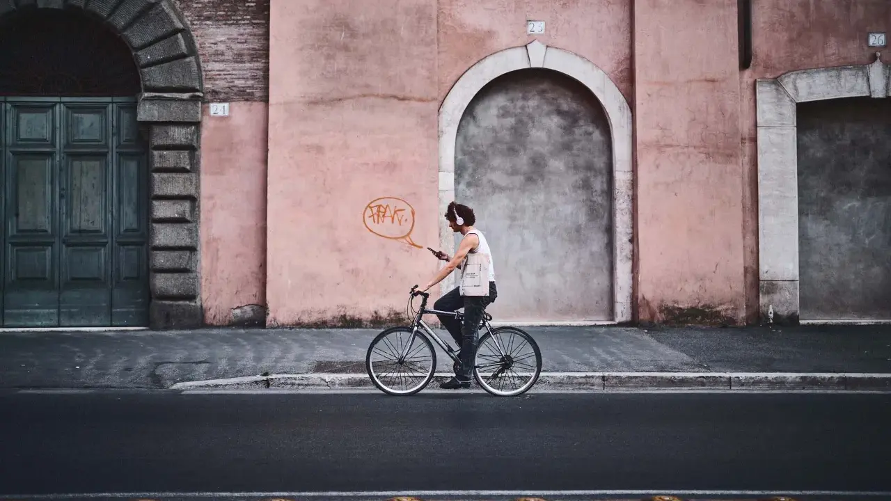 Un ciclista con cuffie ascolta musica mentre pedala, un'istantanea dal reportage di un tour urbano.