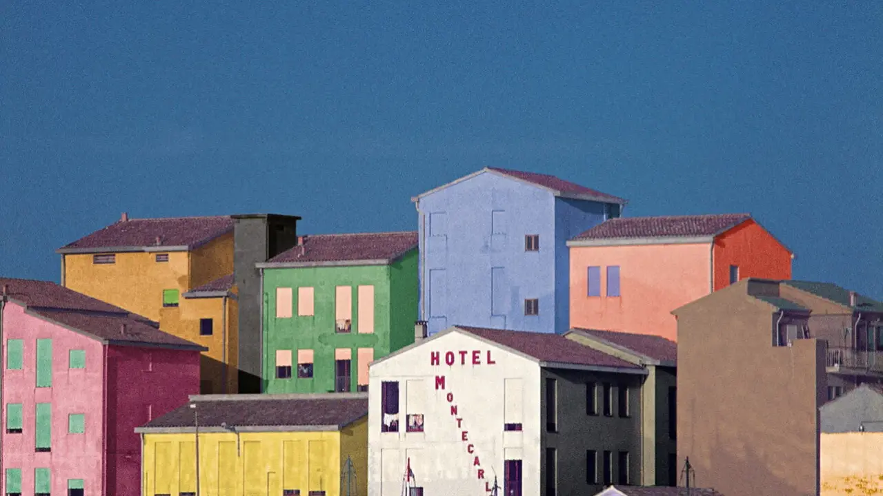 Case colorate e un cielo blu intenso, un paesaggio che ricorda le opere di Franco Fontana.