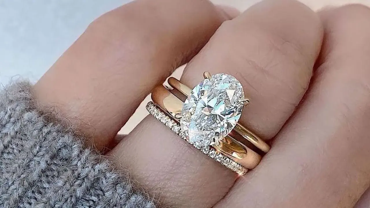 Un solitario anello con diamante ovale, simbolo di un amore eterno e prezioso, adorna un dito.