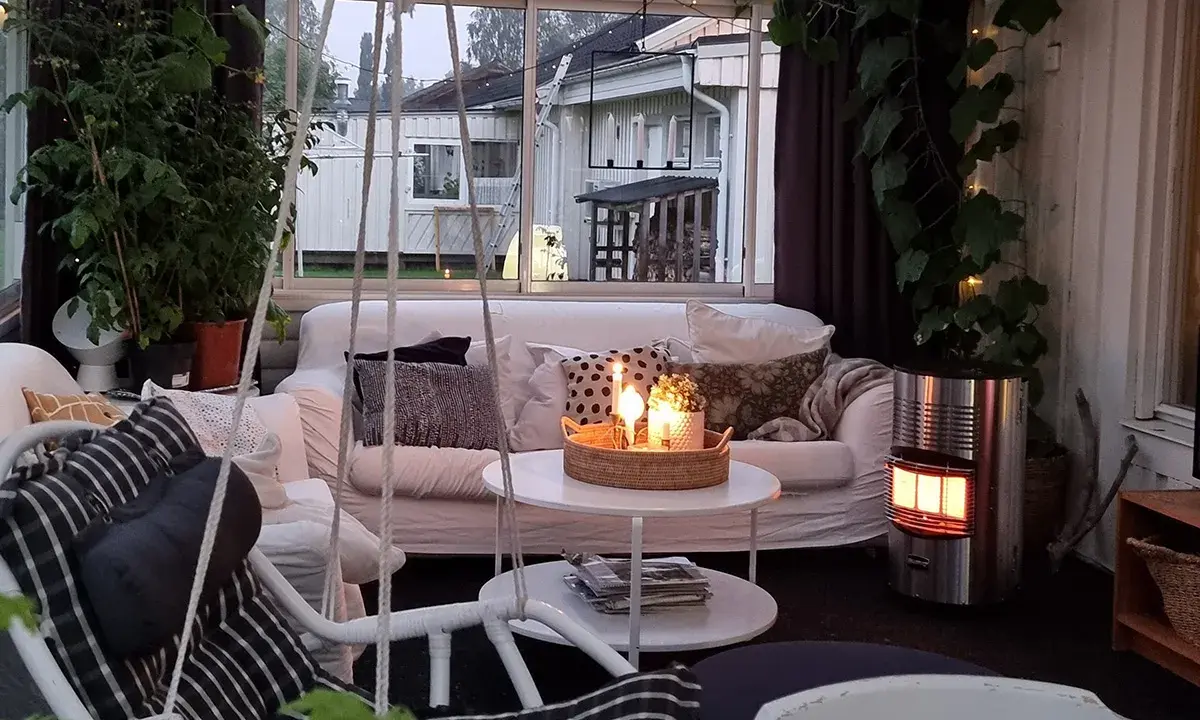 Mysigt uterum med soffa, korgstol och värmare. Perfekt för att inreda uterum för avkoppling.
