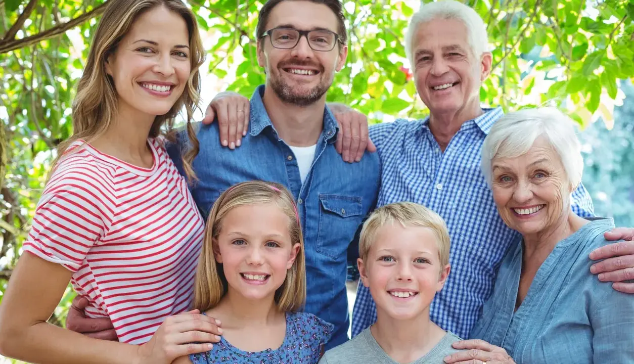 Familia sonriente, de abuelos a nietos, mostrando el factor hereditario en sus rasgos.