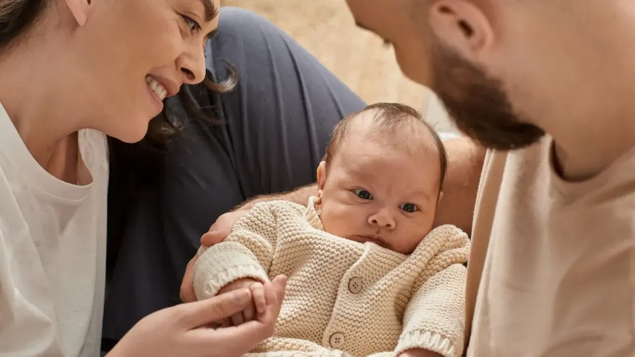 Una madre sonríe a su bebé, mientras el padre lo abraza. A pesar de que mi bebé no tiene apego conmigo, la familia se ve unida.