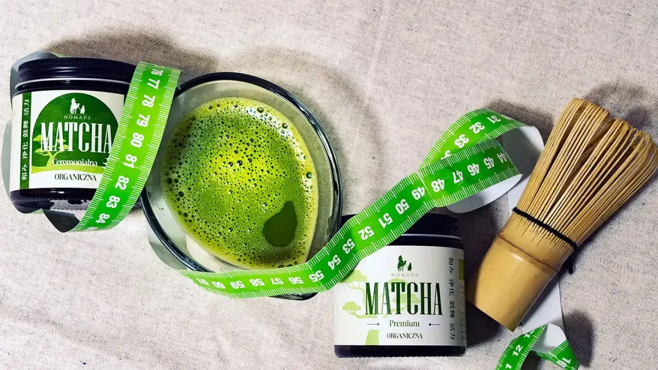 Zielony napój matcha w szklance, obok dwa słoiczki z napisem "MATCHA ORGANICZNA" i miarka krawiecka. Matcha co to? To zdrowy napój.