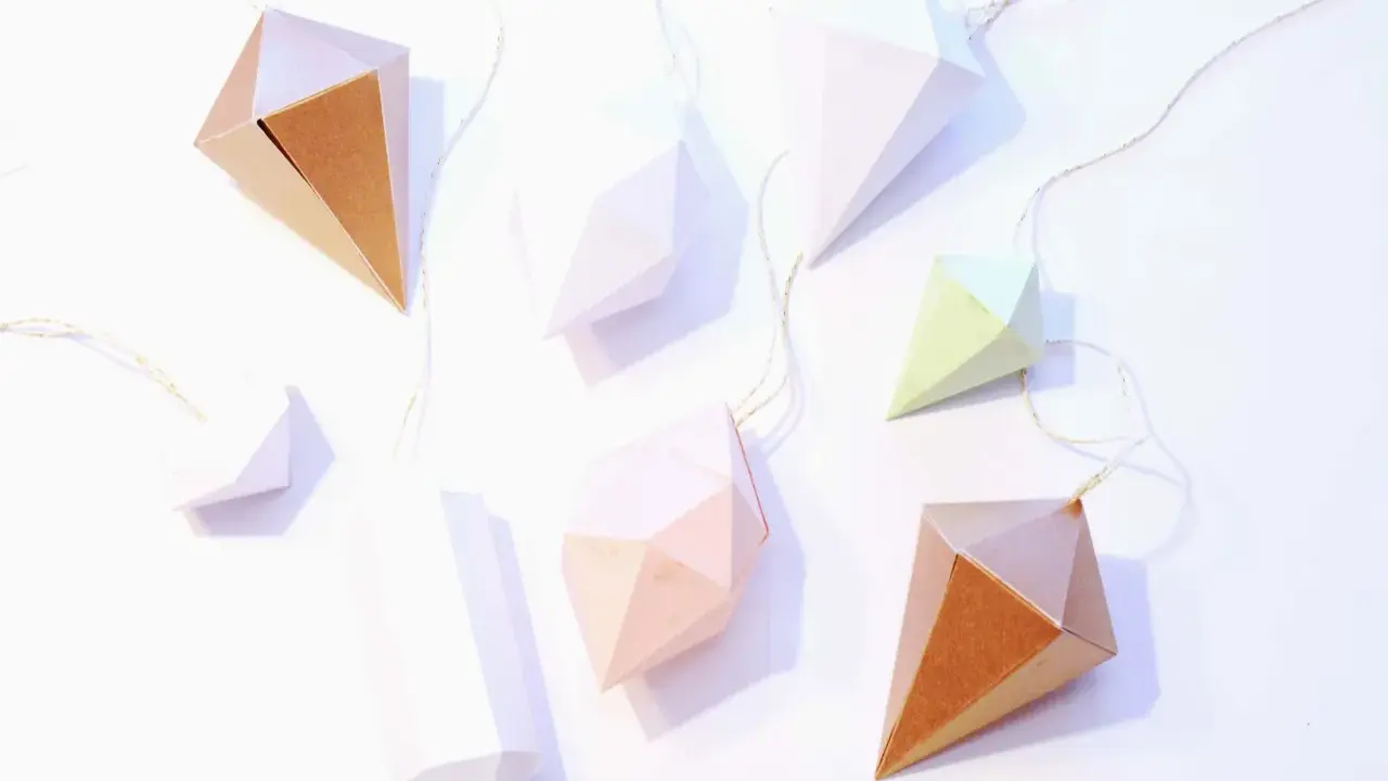 Papierdiamanten in verschiedenen Farben und Größen, die an goldenen Fäden hängen. Eine tolle Idee für eine diamant basteln vorlage.