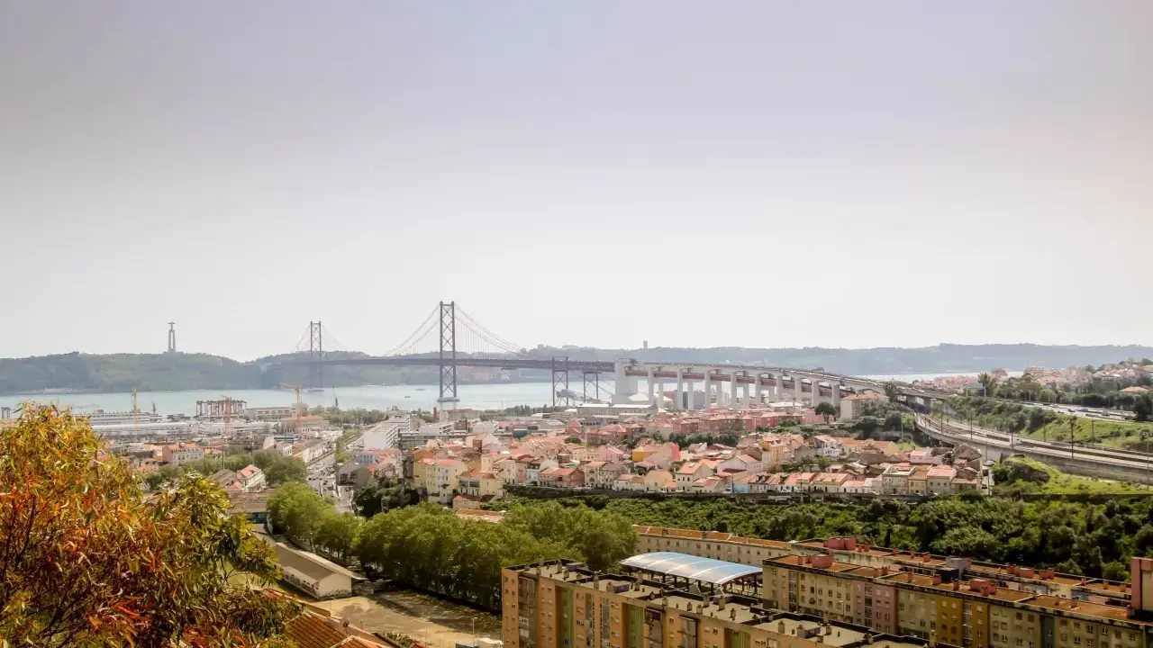 Blick auf Lissabon mit der Hängebrücke und dem Cristo Rei Denkmal. Im Vordergrund die Dächer von Häusern, die an den "Cemitério dos Prazeres" erinnern.