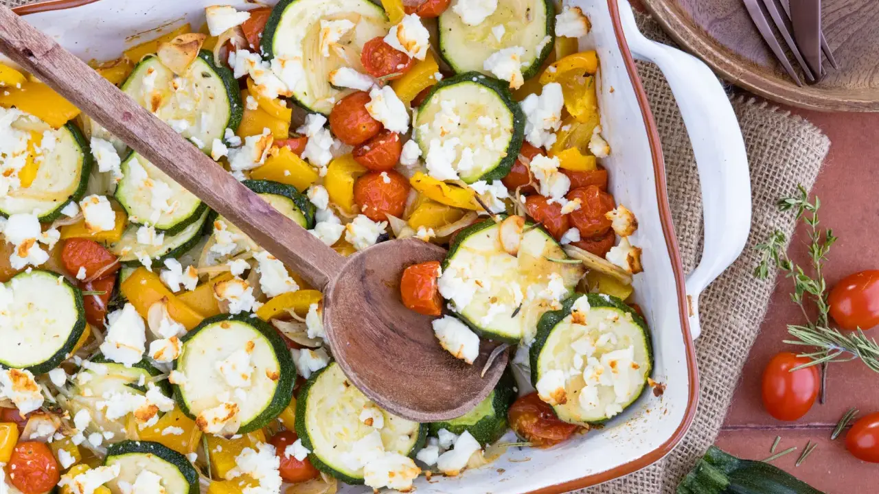 Gebackener Feta mit Zucchini, Kirschtomaten und gelber Paprika in einer Auflaufform, bereit zum Servieren.