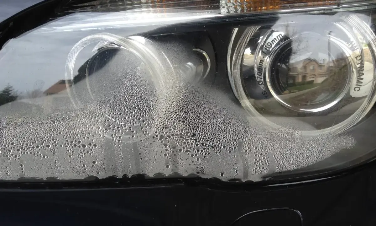 Zaparowany reflektor od środka, z licznymi kropelkami wody na kloszu.