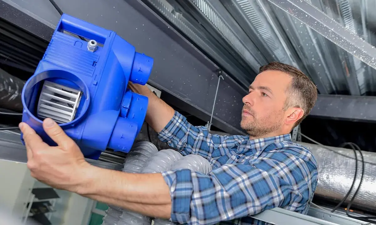 Un technicien installe un nouveau bloc VMC. L'entretien vmc obligatoire garantit un air sain dans votre logement.