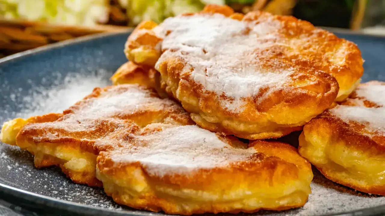 Délicieux Apfelkiechle saupoudrés de sucre glace sur une assiette bleue. Une recette gourmande à essayer !