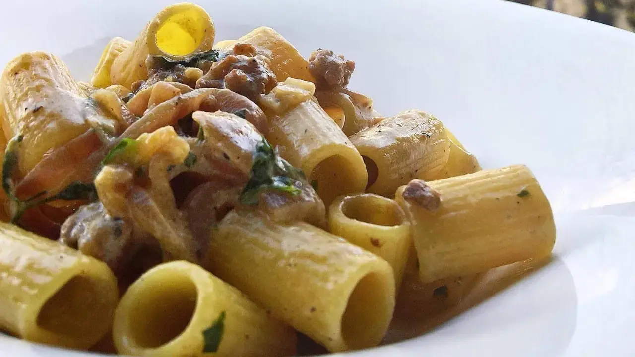 Rigatoni cremosi con salsiccia sbriciolata e erbe aromatiche, un piatto invitante.