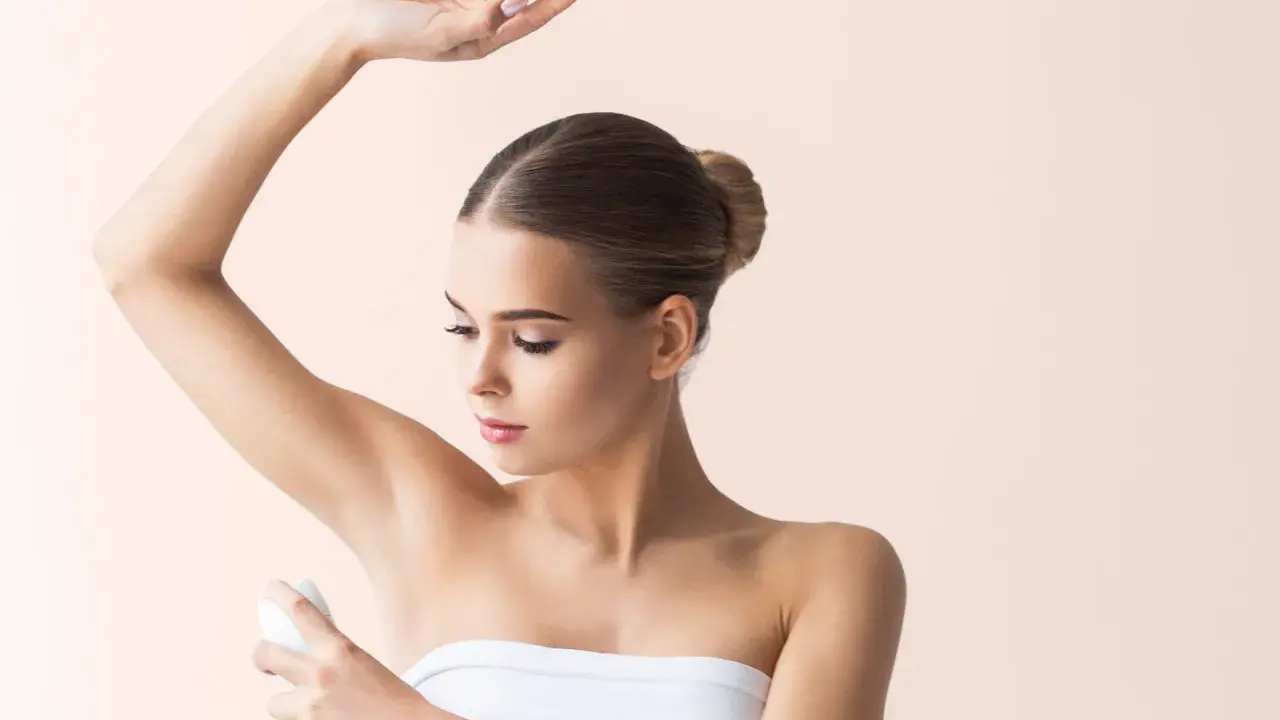 Donna applica deodorante sotto l'ascella. Si discute se l'aluminum chlorohydrate fa male.