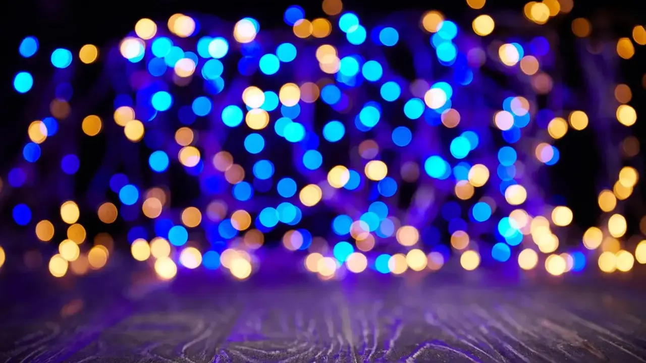 Luci blu e dorate creano un magico effetto bokeh su uno sfondo scuro, con un piano in legno in primo piano.