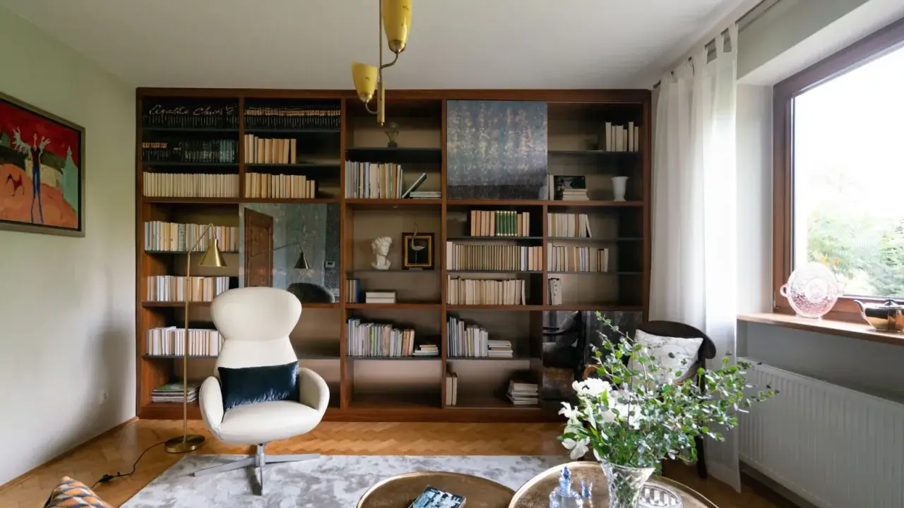 Duży regał na książki za kanapą, wypełniony po brzegi tomami, tworzy przytulną atmosferę.