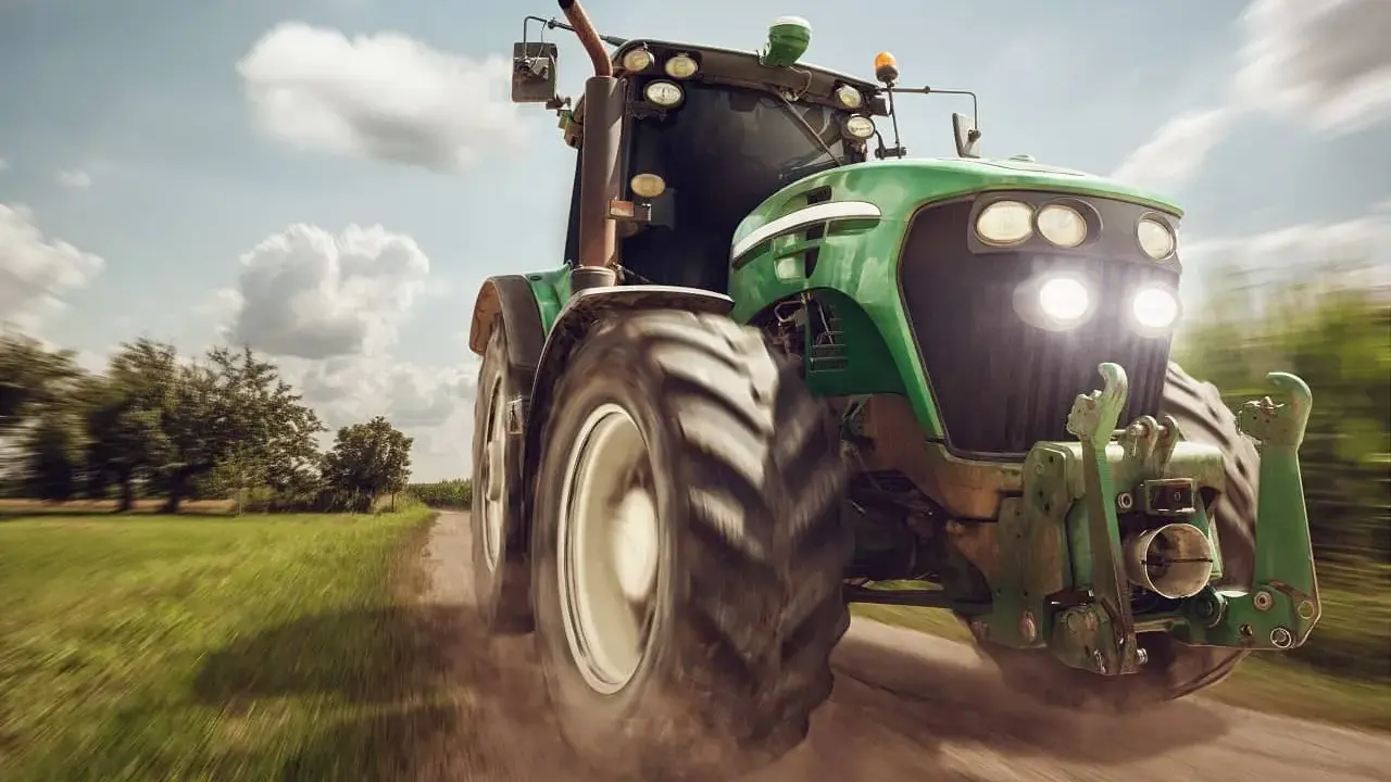 Zielony traktor pędzi po polnej drodze, gotowy do pracy. To maszyna rolnicza, której zakup jest ważną umową kupna sprzedaży.