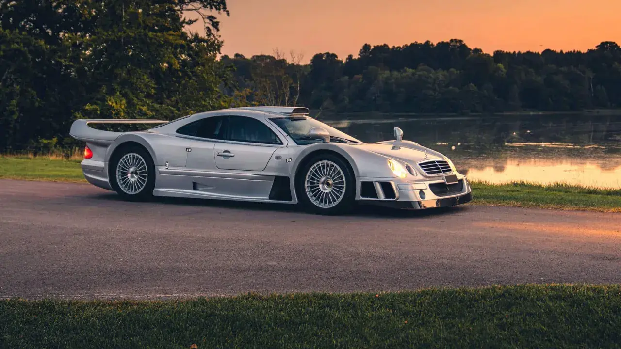 Silberner Mercedes CLK GTR am Seeufer bei Sonnenuntergang. Ein Blick auf dieses seltene Sammlerstück, das den Begriff "Mercedes CLK GTR Preis" neu definiert.