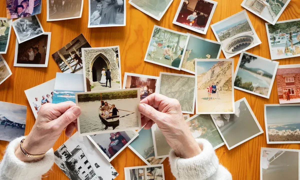 Mani anziane sfogliano vecchie foto stampate su un tavolo di legno, un modo per conservare le foto stampate e i ricordi.