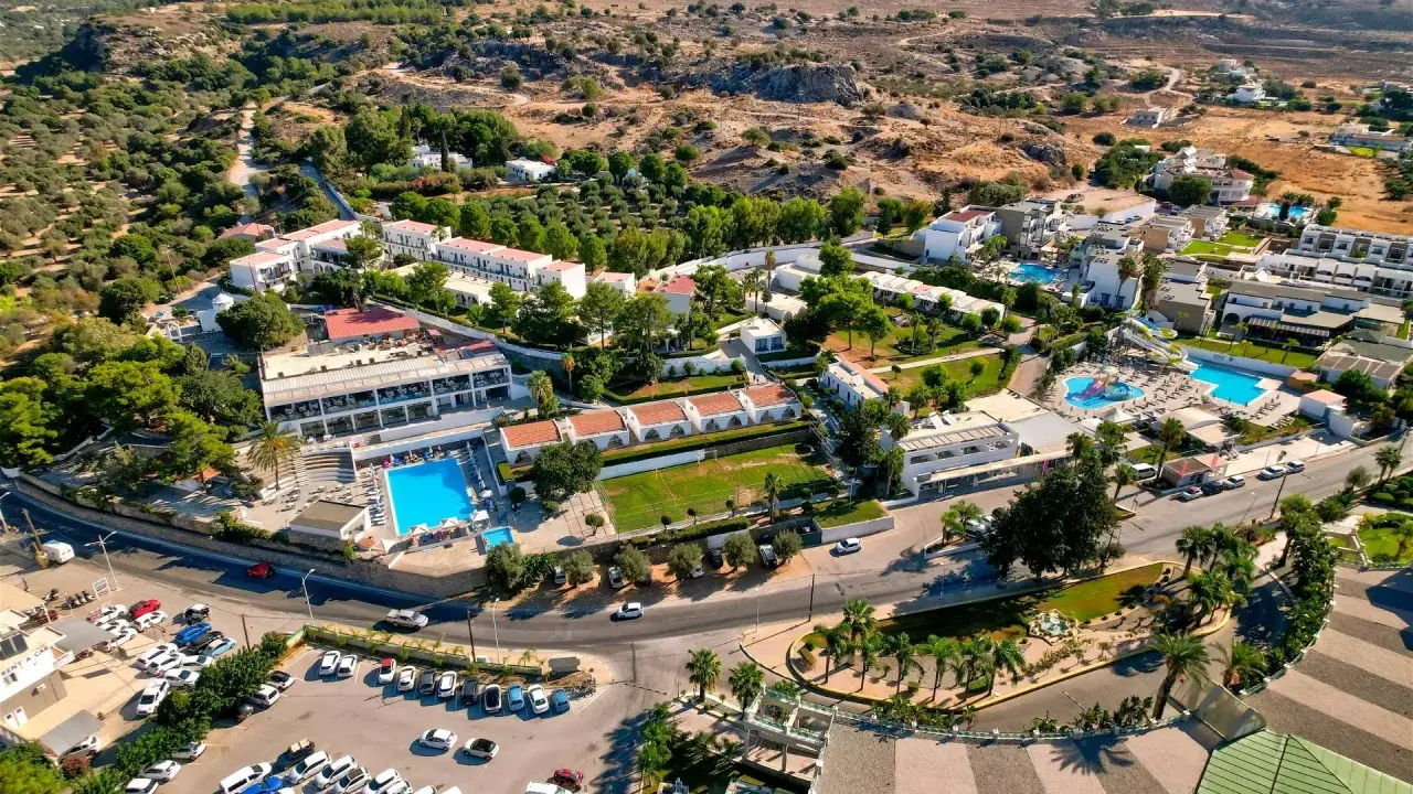 Widok z lotu ptaka na hotel Ellia Rodos z basenami, zjeżdżalniami i parkingiem pełnym samochodów.