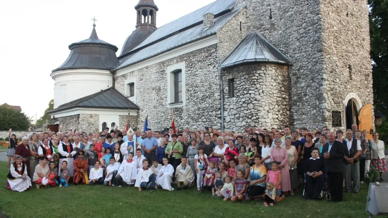 Wielka grupa ludzi, w tym dzieci i duchowni, pozuje przed zabytkowym kościołem parafii Skarżysko.