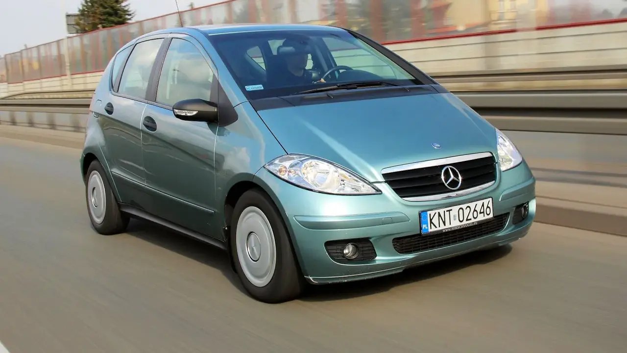 Turkusowy Mercedes A170 na drodze, z widocznym kierowcą.