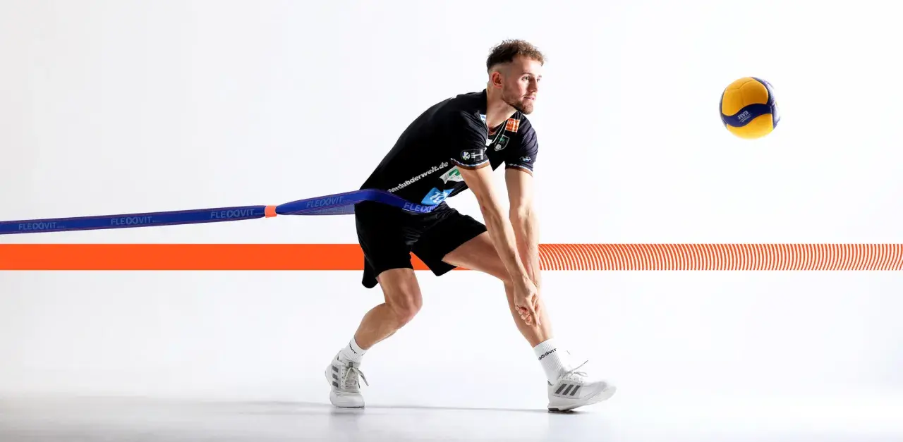 Volleyballspieler im Krafttraining mit Widerstandsband, bereit für den Aufschlag.