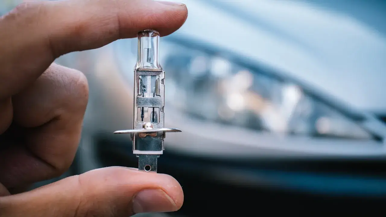 Un dedo sostiene una bombilla de coche, lista para iluminar el camino con sus luces largas.