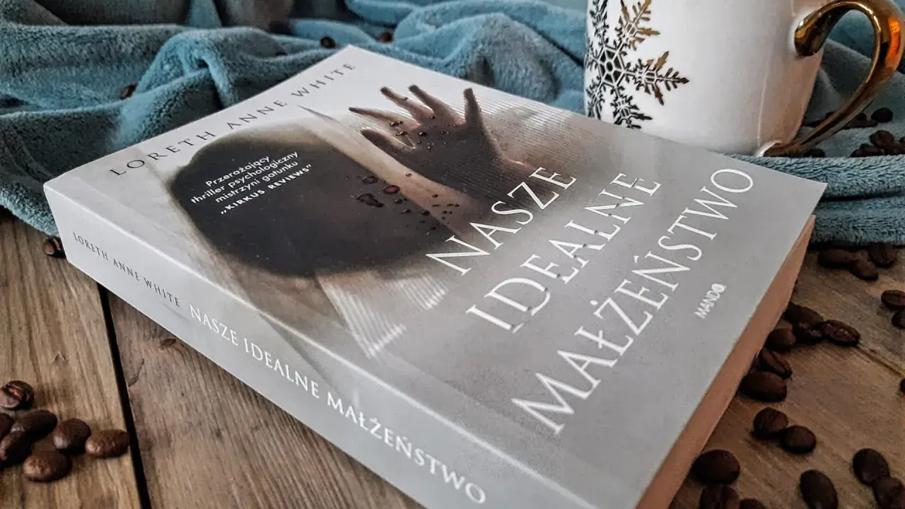 Książka "Nasze idealne małżeństwo" na drewnianym blacie, obok filiżanki i ziaren kawy.