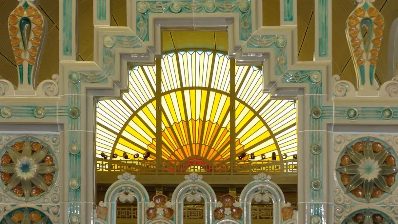 Détails ornementaux en céramique, style art déco, encadrant une verrière jaune rayonnante.