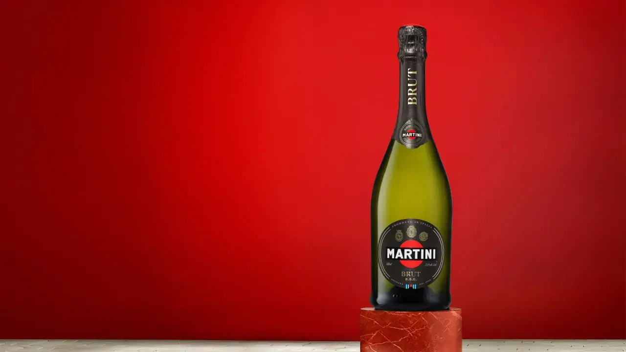 Butelka Martini Brut 7.5% alc. vol. na tle czerwonej ściany.