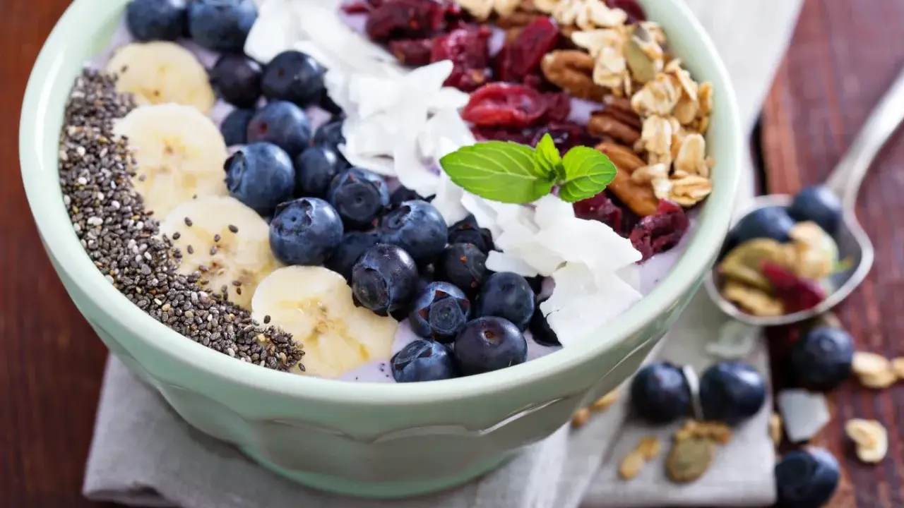 Miseczka pełna super foods: jagody, banany, nasiona chia, płatki kokosa, żurawina i granola. Idealne śniadanie.